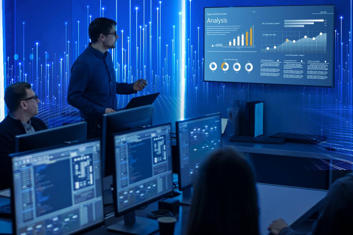 Colleagues reviewing data on monitor display with blue data dots and beams in background.