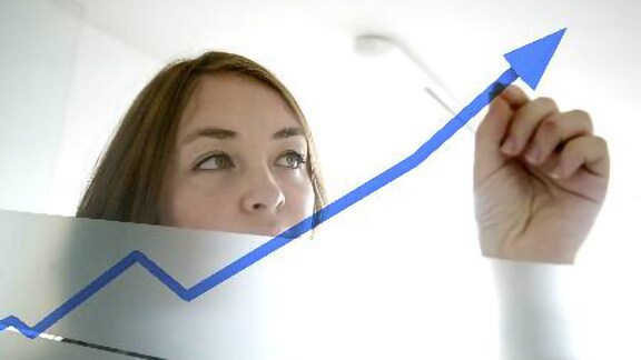 A female employee drawing an upwards arrow on a whiteboard