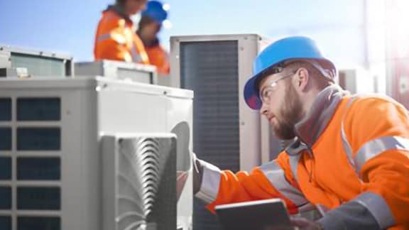 An engineer in safety suit and helmet inspecting a hvac device